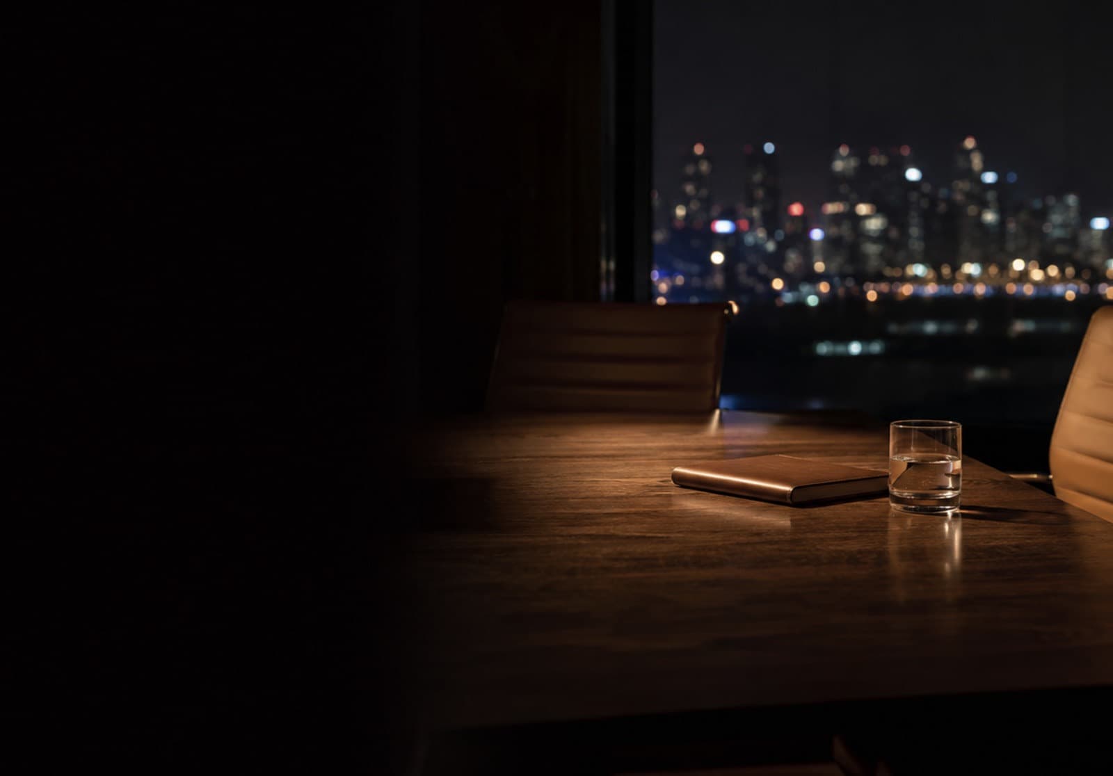 Empty meeting table at night, city lights out of focus